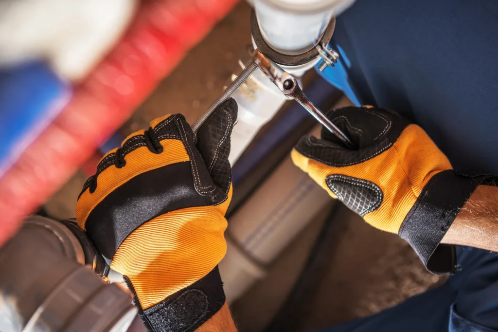 Licensed NYC plumber tightening a pipe fitting during a leak repair